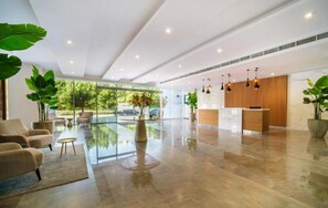 A spacious lobby with a reception desk, seating area, and large windows offering a view of the outdoors. - Elegant 1BR at Bloom - Host & Stay (Dubai)