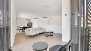 Un salon moderne avec un canapé, deux tables rondes et un coin repas avec des chaises.