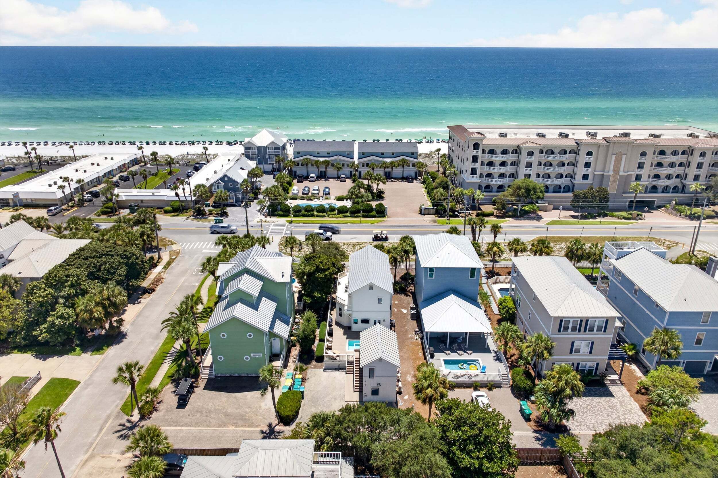 A coastal hotel with multiple buildings, a parking lot, and a view of the ocean.