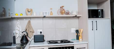 A modern kitchen with a stove, oven, and microwave. There are shelves with kitchenware and a decorative bicycle.