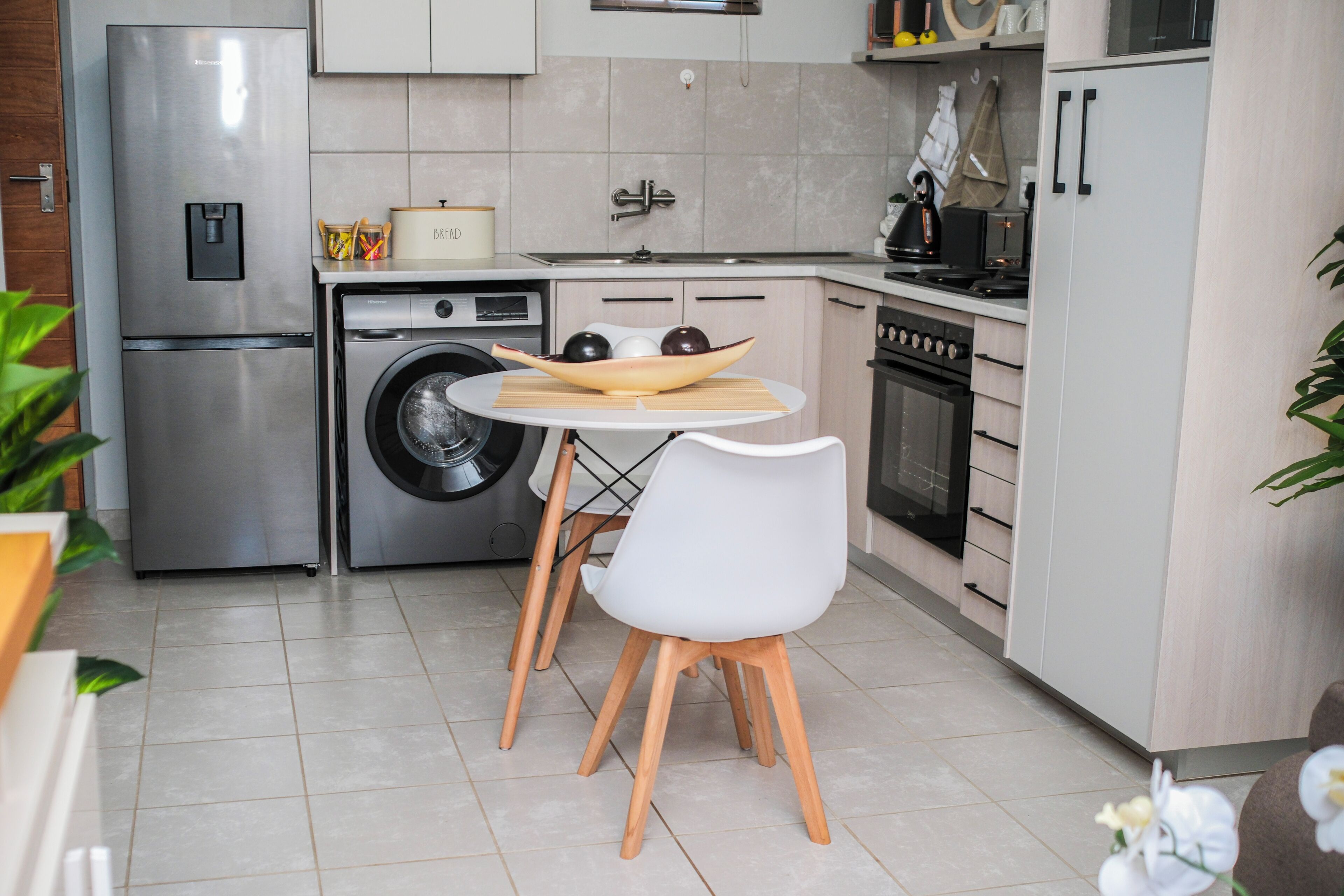 Une cuisine moderne équipée d’appareils électroménagers en acier inoxydable, d’un lave-linge et d’un coin repas avec une table et des chaises.