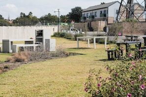 An outdoor area with a concrete structure, a white table, and a bench. - Cozy 1-bedroom Apartment in Secure Estate, Tshwane (Centurion)