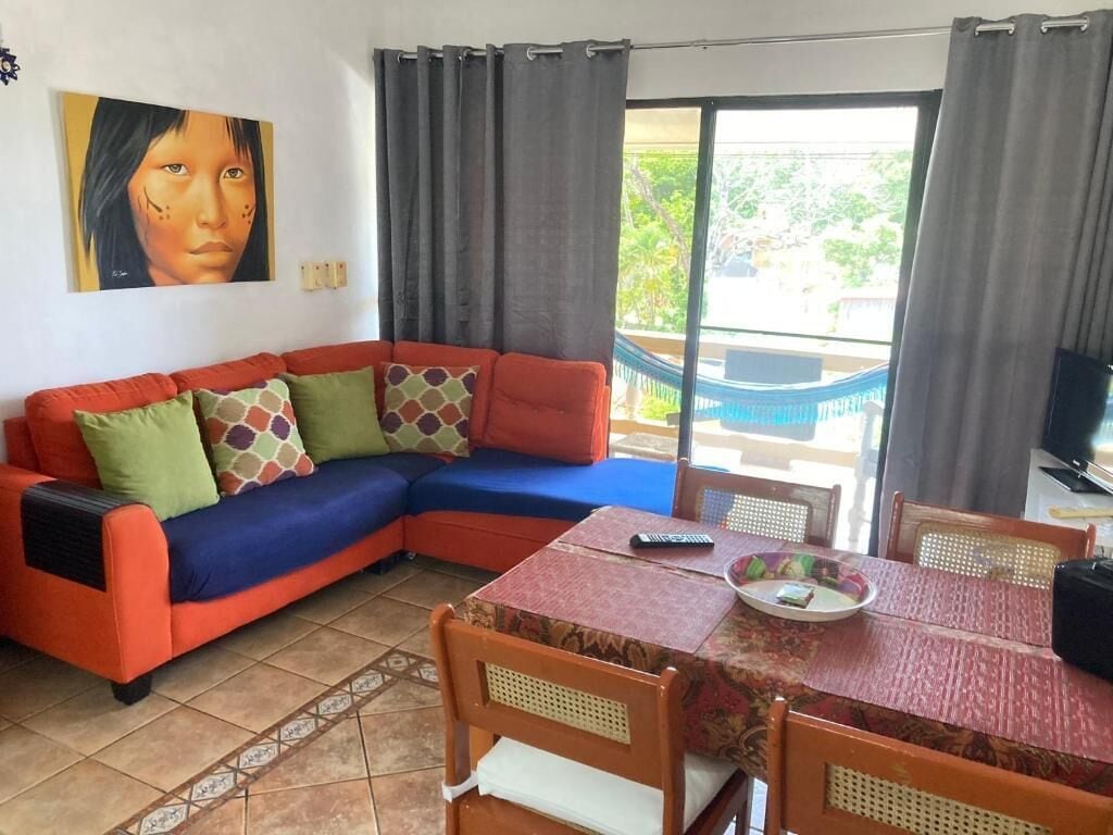 Ein Wohnzimmer mit einer Couch, einem Esstisch und Blick auf einen Balkon.