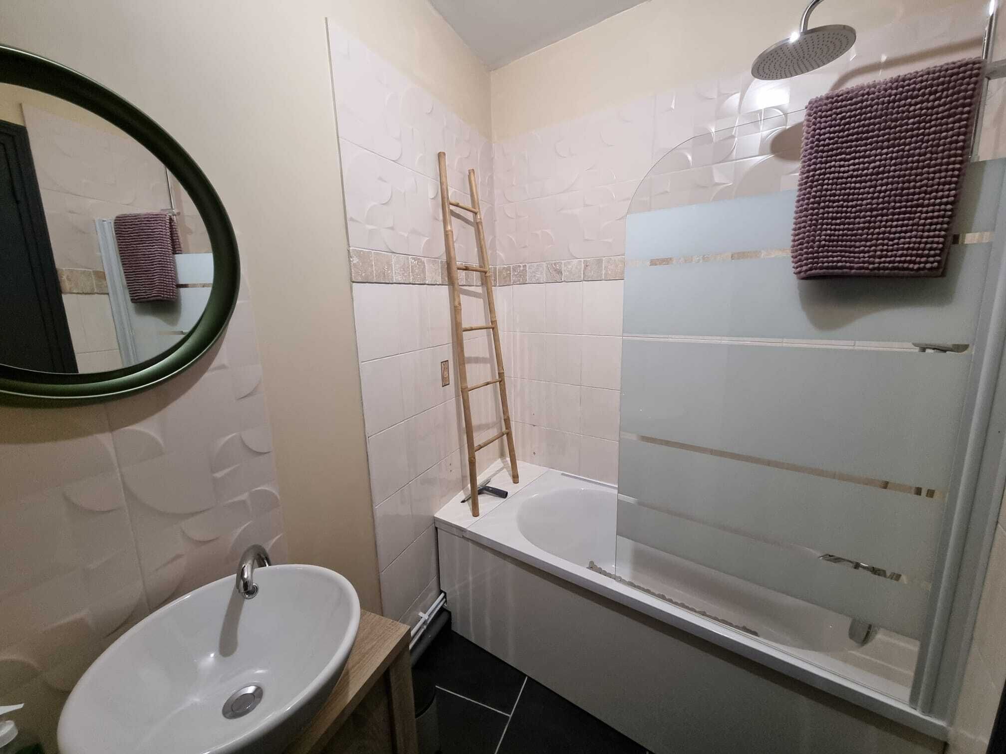 A bathroom with a sink, mirror, and shower.