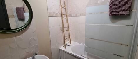 A bathroom with a sink, mirror, and shower.