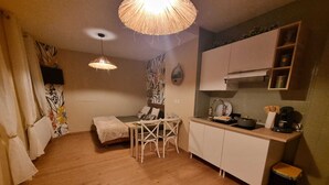 A compact living space with a kitchenette, a dining area, and a small seating area. - Le Pti Marais, a 3-star studio on the outskirts of Saint-Omer (Saint-Martin-lez-Tatinghem)