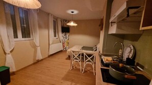 A compact kitchen with a dining area, a small table, and a single hanging light fixture. - Le Pti Marais, a 3-star studio on the outskirts of Saint-Omer (Saint-Martin-lez-Tatinghem)