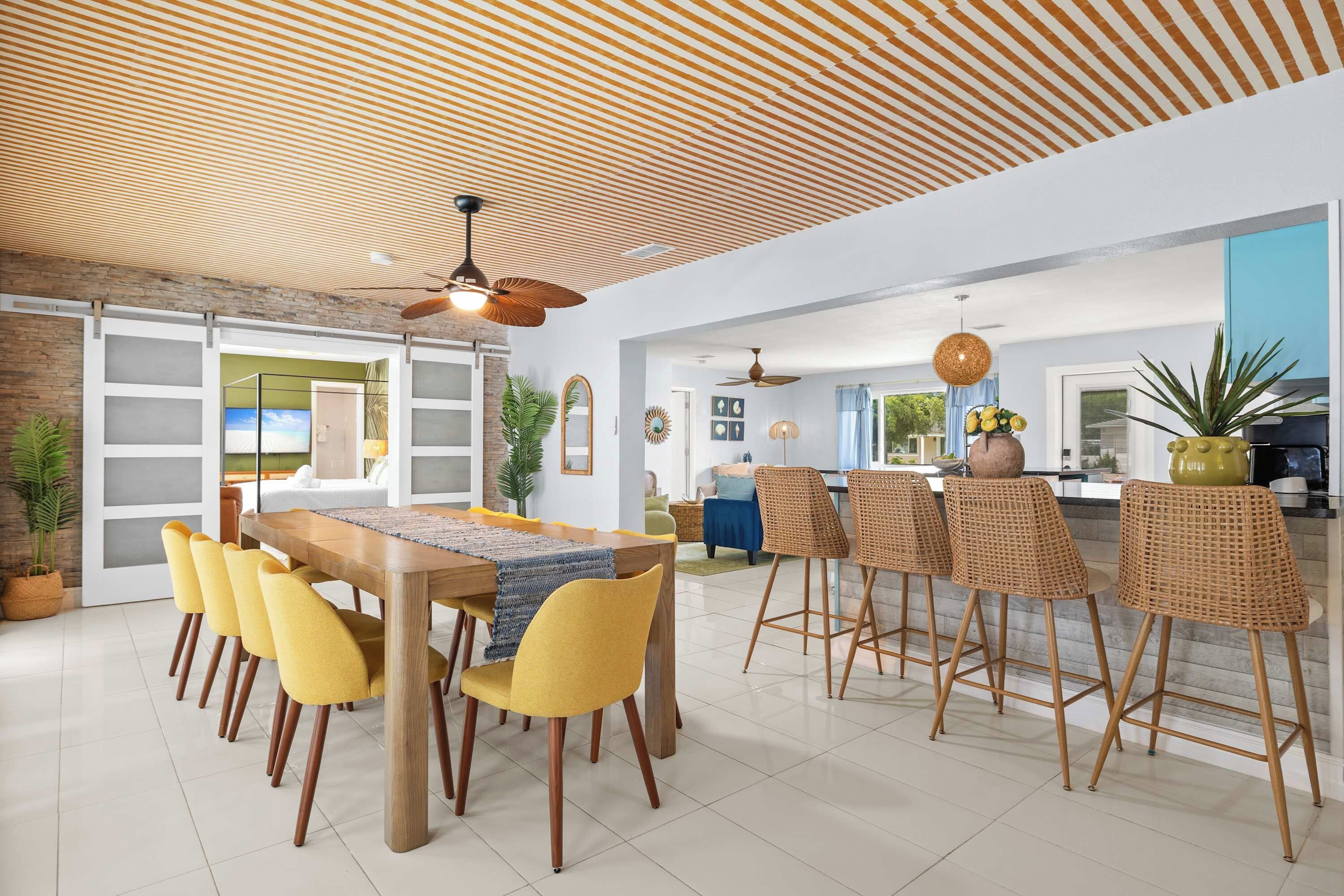 A modern dining area with a wooden table, yellow chairs, and a ceiling fan.