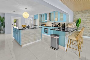 Una cocina moderna con armarios azules, una isla central y una barra con taburetes.