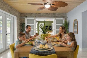 A dining area with a wooden table, chairs, and a ceiling fan.