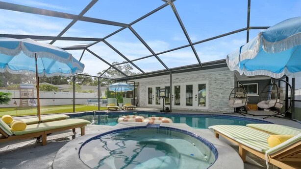 Ein Hallenbad mit Liegestühlen und Sonnenschirmen, umgeben von einer Glaskonstruktion.