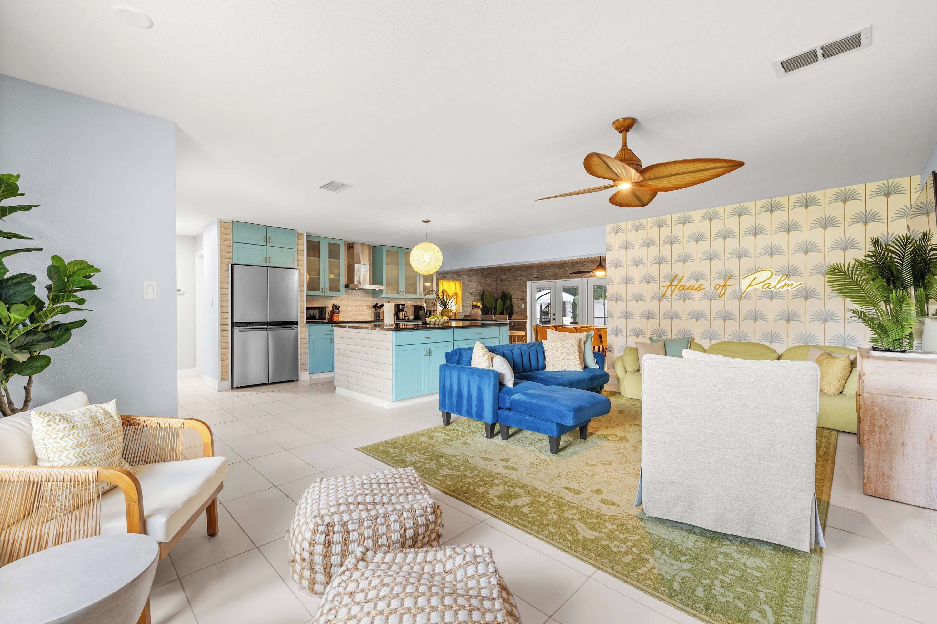 Una sala moderna con un sofá azul, un sillón blanco y un comedor con una mesa azul.
