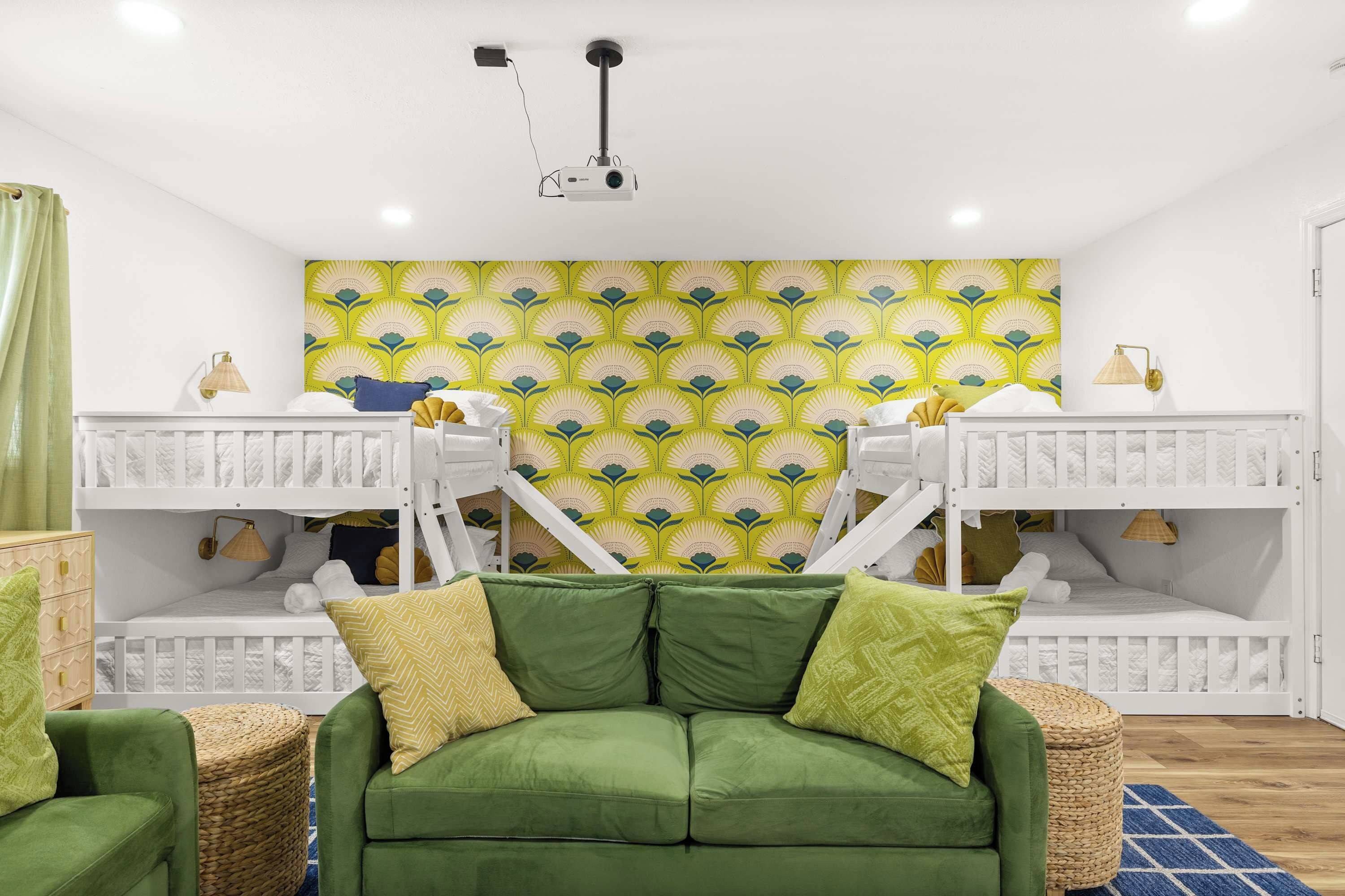 A children's room with bunk beds, a green sofa, and a projector on the ceiling.
