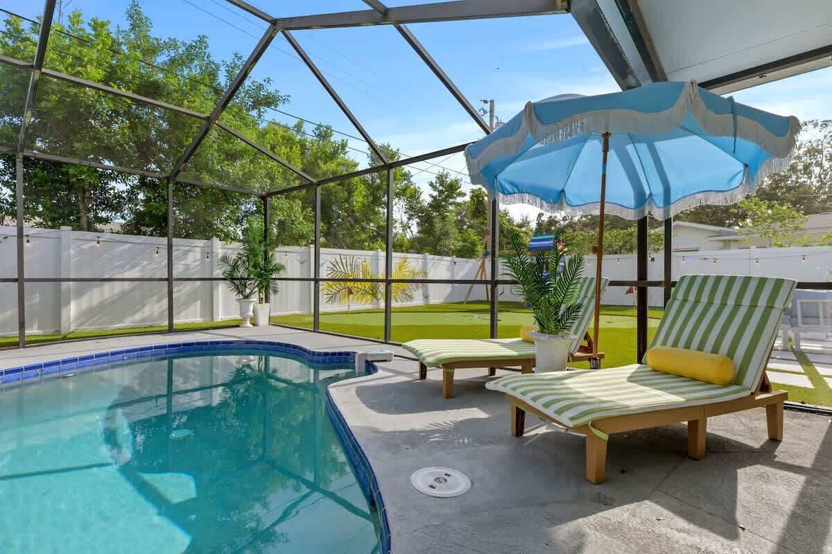 Ein Poolbereich mit Glasumrandung, Liegestühlen und Sonnenschirm.