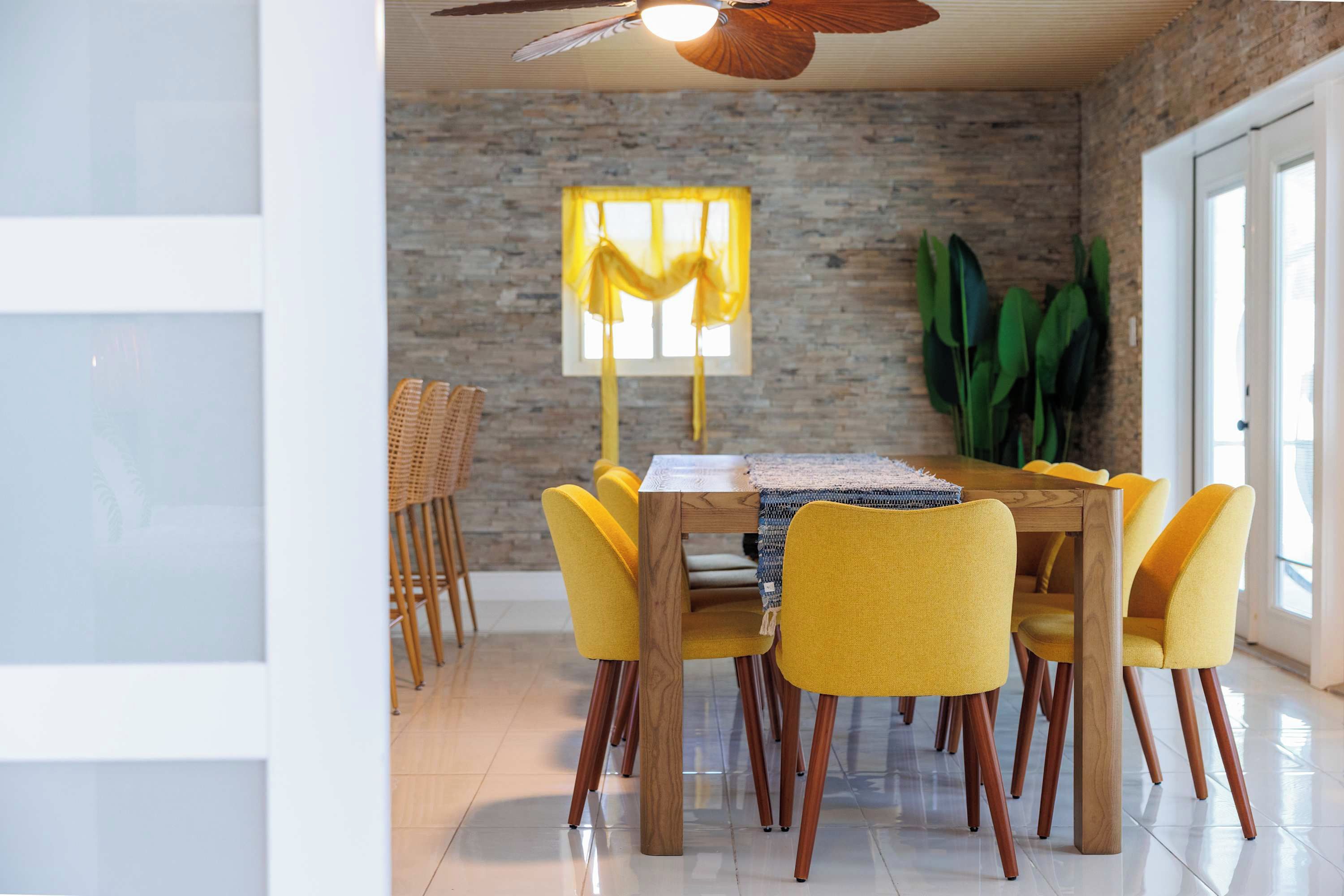 A dining area with a wooden table, yellow chairs, and a ceiling fan.