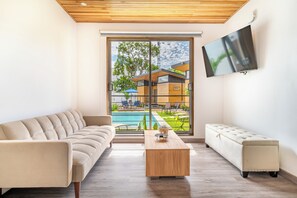 A modern living room with a sofa, a coffee table, and a TV mounted on the wall. - Luxurious 6-Unit Oasis < 1 Mi to Playas Del Coco! (Playas del Coco)
