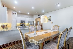 A dining area with a wooden table, upholstered chairs, and a chandelier. - Grill & Yard! Family Escape, 8 Mi to Dtwn Odessa (Odessa)
