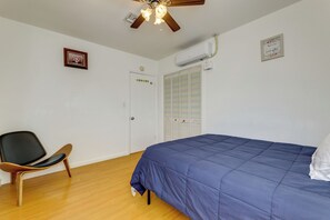 A bedroom with a bed, a chair, a ceiling fan, an air conditioning unit, and a door with a colorful striped closet. - 12 Mi to Downtown LA: Central SoCal Base (Rosemead)
