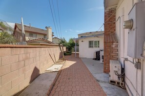 A narrow paved pathway between buildings, with a brick wall on one side and a white building on the other. - 12 Mi to Downtown LA: Central SoCal Base (Rosemead)