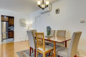 A dining area with a wooden table and four chairs, a chandelier, an air conditioning unit, and a wall-mounted clock. - 12 Mi to Downtown LA: Central SoCal Base (Rosemead)