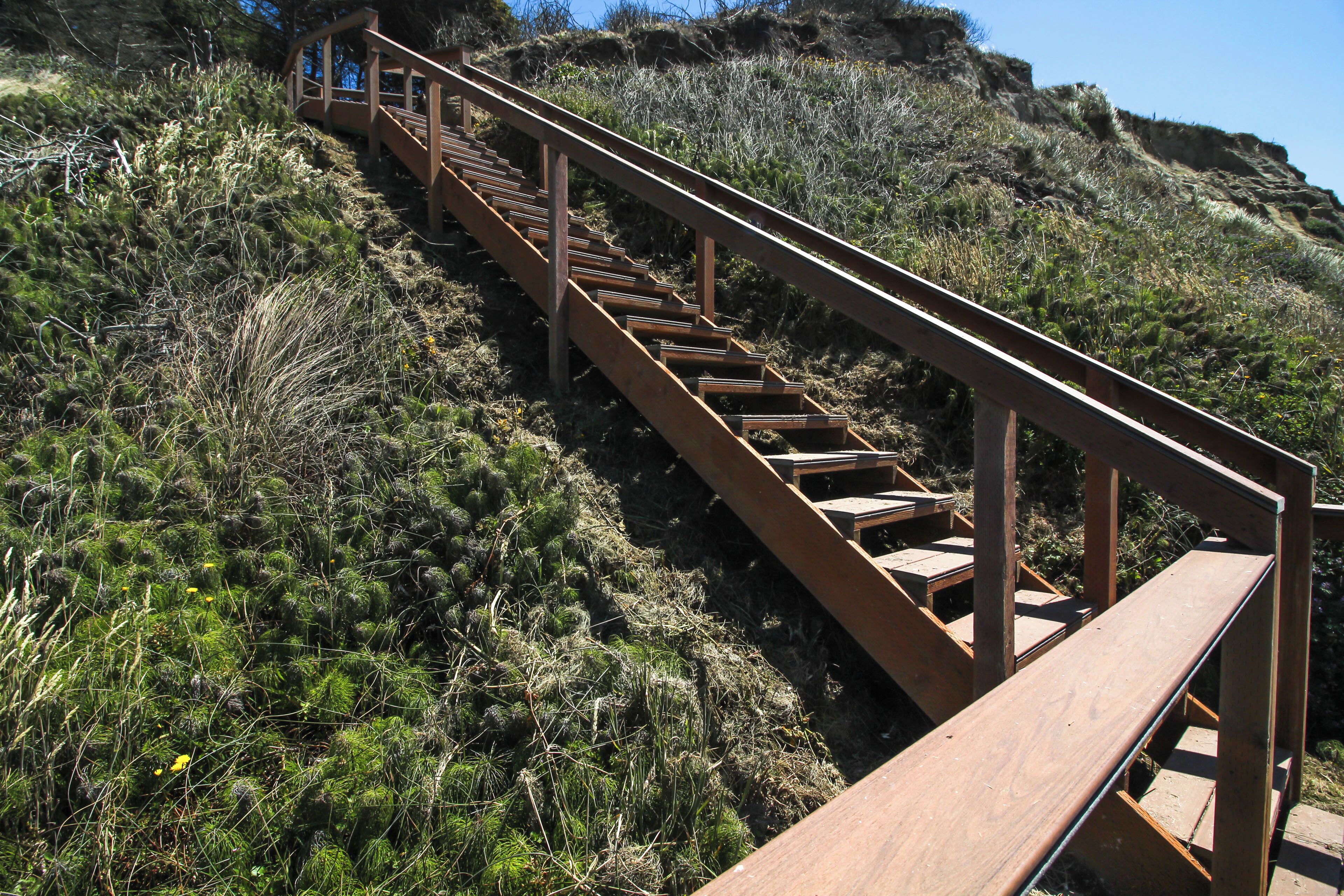 Una escalera de madera que sube una colina, con barandillas a ambos lados.