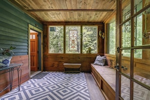 A cozy cabin interior with a bench, a door, and a window with a stained glass view. - Deck & Wooded Views! 2 Mi to Frederick Gunn School (Washington)
