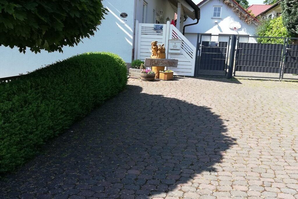 Ein gepflasterter Weg führt zu einem verschlossenen Eingangsbereich mit Briefkasten und Briefkastensäule.