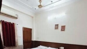 A hotel room with two beds, a wooden headboard, a ceiling fan, and a red curtain.