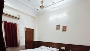 A hotel room with two beds, a wooden headboard, a ceiling fan, and a red curtain.