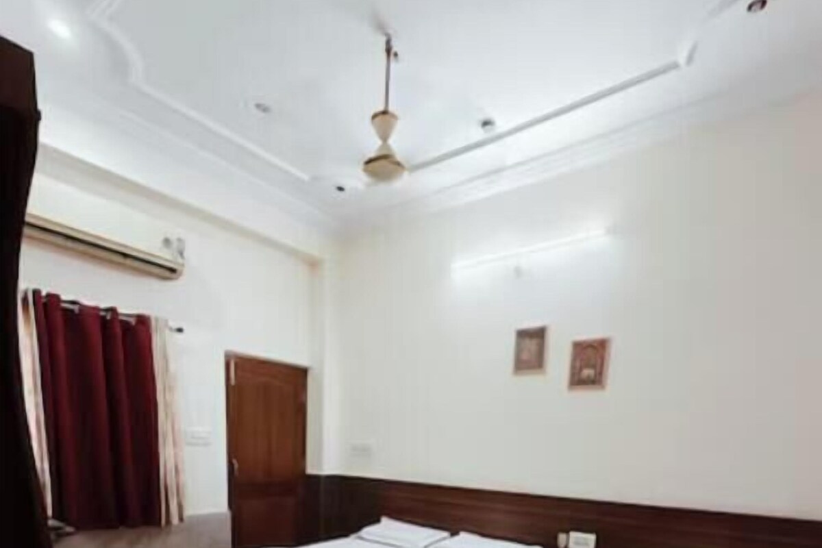 A hotel room with two beds, a wooden headboard, a ceiling fan, and a red curtain.
