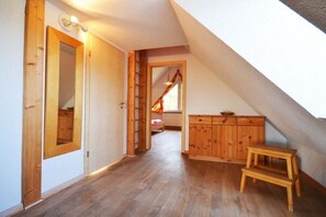 A room with wooden flooring, a wooden cabinet, a step stool, and a door leading to another room. - Holiday apartment with 1 bedroom (Kölpinsee \/ Loddin)