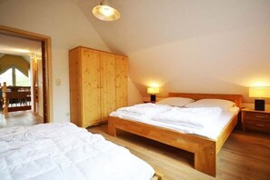 Een slaapkamer met een houten bed, een kledingkast en twee bedlampjes.