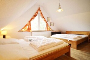 Een slaapkamer met twee bedden, een raam met gordijnen, een bedlamp en een houten hoofdbord.
