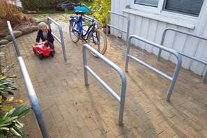 A child playing with a toy car and a bicycle in a paved outdoor area with metal railings. - Holiday apartment with 1 bedroom (Kölpinsee \/ Loddin)