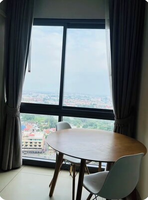 Ein Zimmer mit einem großen Fenster, einem runden Tisch und zwei Stühlen.