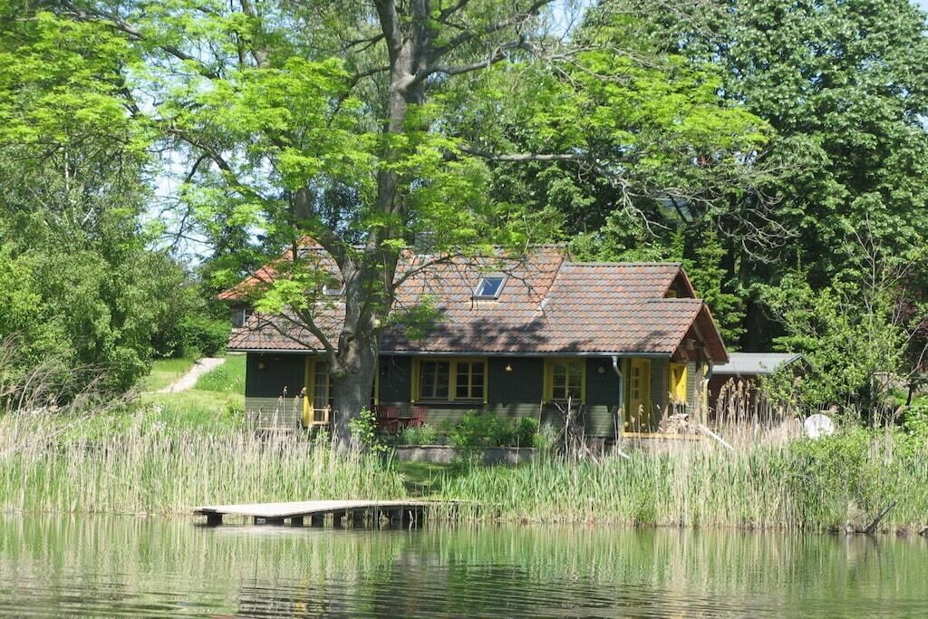 A cabin with a dock, surrounded by trees and a body of water.