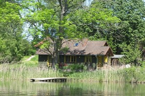 Eine Holzhütte mit Steg, umgeben von Bäumen und einem See.