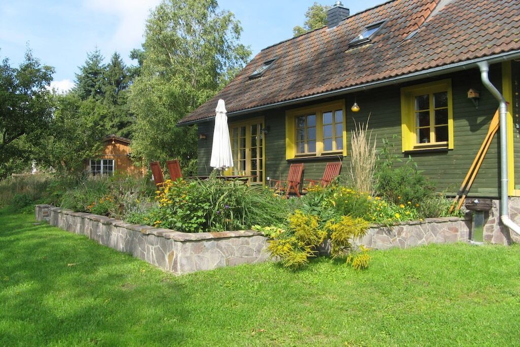A house with a stone foundation, a green exterior, and yellow windows.