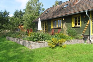 Een huis met een stenen fundering, een groene gevel en gele ramen.