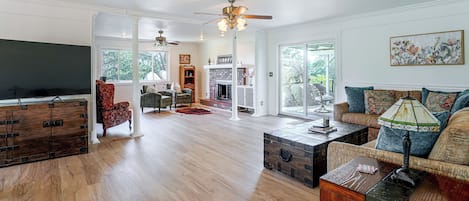 A spacious living room with hardwood flooring, a fireplace, and a large window.