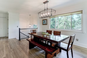 A dining area with a wooden table, benches, and chairs. There is a window with a view of trees and a chandelier above. - 1 Mi to Courthouse Plaza! Home w/ Deck + Fireplace (Prescott)