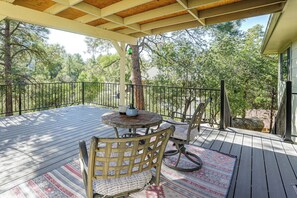 A covered outdoor deck with a round table and chairs, surrounded by a wooden railing. - 1 Mi to Courthouse Plaza! Home w/ Deck + Fireplace (Prescott)
