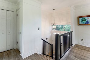 A staircase with a black railing leading to a landing, a white door on the left, and a window with a view of greenery. - 1 Mi to Courthouse Plaza! Home w/ Deck + Fireplace (Prescott)