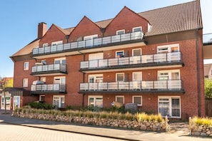 A multi-story brick building with balconies and a stone-lined pathway. - Apartment in Juist with swimming pool (Juist)