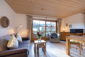 A cozy living room with a sofa, a small table, a chair, and a dining table. - Holiday apartment with 1 bedroom (Obermaiselstein)