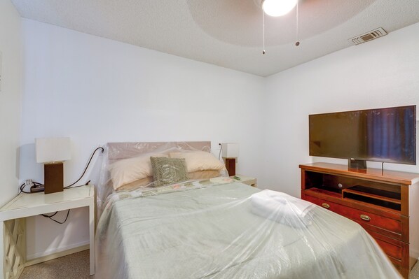 A bedroom with a bed, a TV, a dresser, and bedside lamps.