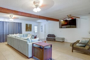 A living room with a sofa, a coffee table, a chair, and a ceiling fan.