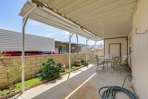 Ein überdachter Patio-Bereich mit Tisch und Stühlen, einer Ziegelwand und Kübelpflanzen.