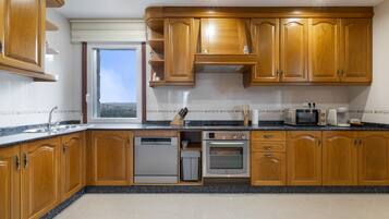Una cocina con armarios de madera, lavavajillas, horno y ventana con vistas.