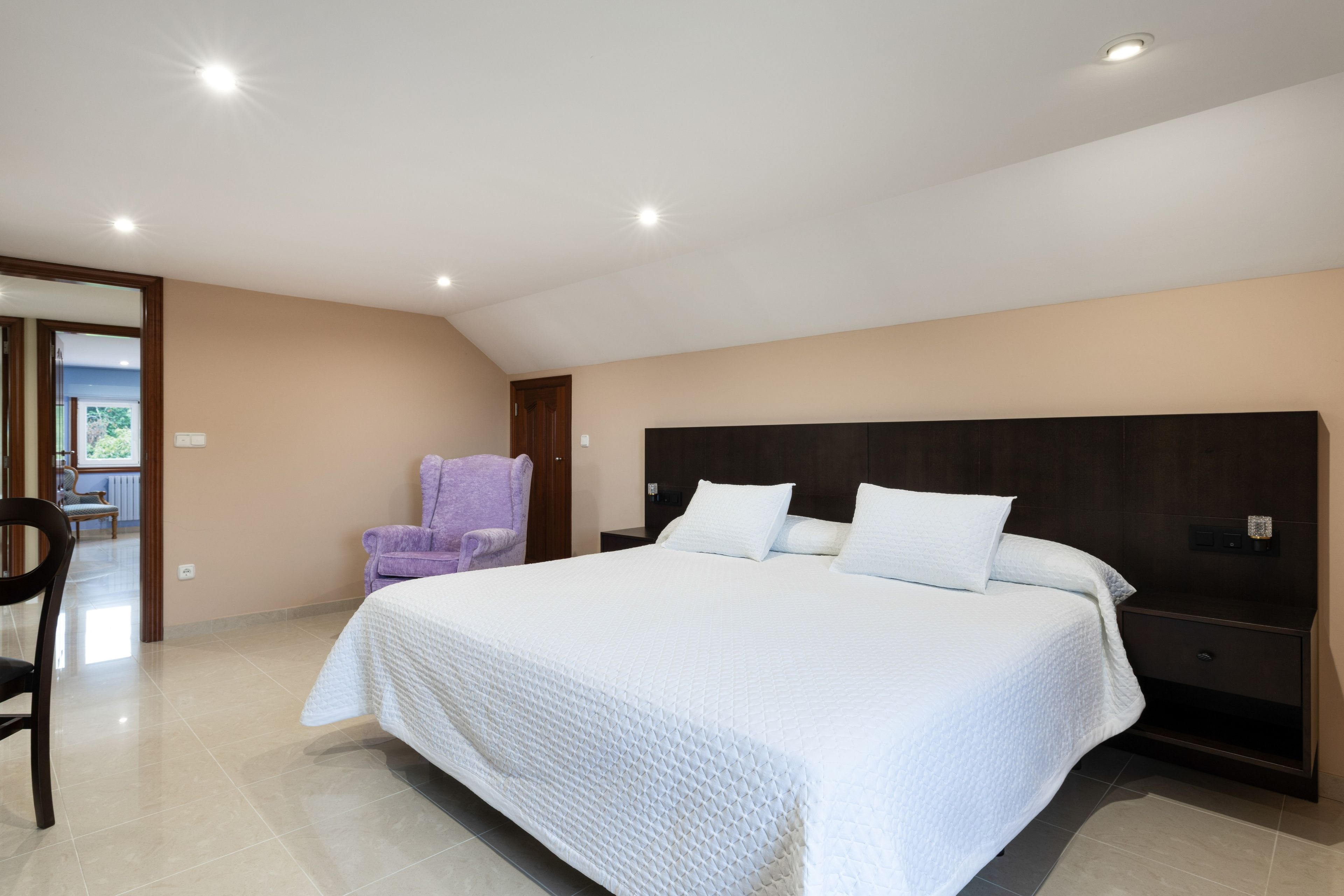 Una camera da letto con un letto grande, una sedia e un comodino.